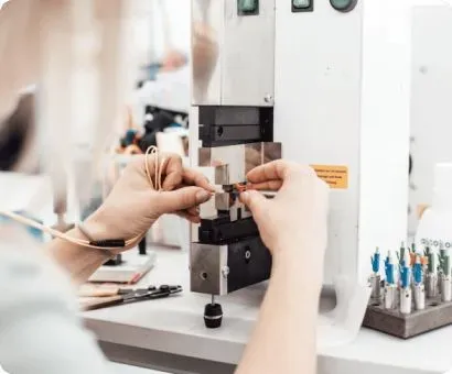 Hands operating a wire crimping machine.